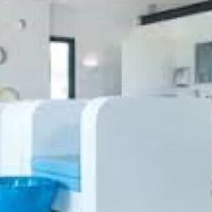 A moment of relaxation features a modern nail salon interior with white minimalist chairs and bright blue pedicure bowls. Natural light and circular wall cutouts enhance the clean, stylish space designed for stress relief and comfort.