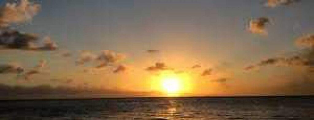 Bubbels op de laars vangen het zonlicht op terwijl een feloranje zonsondergang reflecteert over de oceaan. Zachte wolken verspreiden zich over de lucht en versterken de vredige en serene sfeer van de scène.