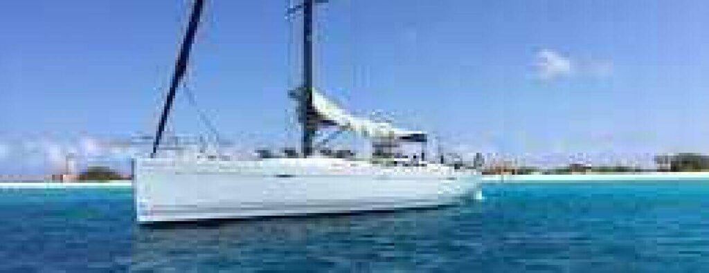 Experience the Half Day Trip Watersport: enjoy a white sailboat on clear blue water near a sandy beach, under a bright sky with lush greenery lining the shore—a perfect escape for relaxation and adventure.