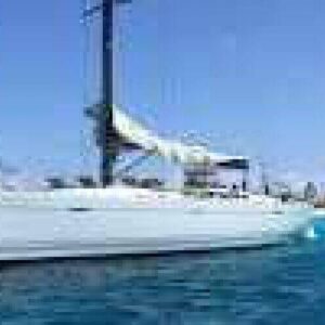 Experience the Half Day Trip Watersport: enjoy a white sailboat on clear blue water near a sandy beach, under a bright sky with lush greenery lining the shore—a perfect escape for relaxation and adventure.