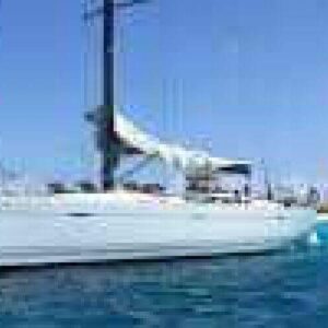 Experience the Klein Curacao Day trip: a white sailboat floats on clear blue water near a sandy shore, under a bright sky with few clouds. The distant coastline and sparse greenery complete the stunning view.