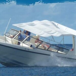 The Klein Curacao Speedboat Adventure taxi service speeds across calm blue water with several passengers seated under a white canopy, enjoying the ride and ocean spray beneath a partly cloudy sky.
