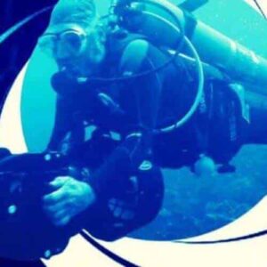 A scuba diver in full gear with a Private DPV dive setup holds an underwater camera, framed by the iconic swirling gun barrel graphic from James Bond films. The blue-tinted image features the 007 with gun symbol in the bottom right corner.