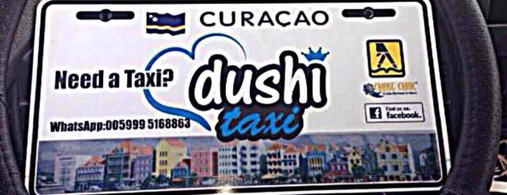 The “Taxi to Punda” Curacao taxi sign features a blue heart, Curacao flag, phone and Facebook icons, plus a Willemstad waterfront image. Book your ride easily—logos and contact info appear on a clean white background.