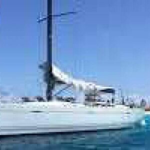 Experience our Sailing Trips Per Day with Overnight Stay: relax on a white sailboat anchored near a sandy beach with turquoise waters and sparse greenery—perfect for day adventures or nights under clear blue skies.