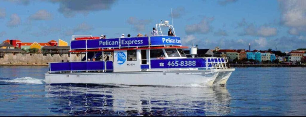 Snorkel the West, a white and blue two-level ferry, glides across calm waters as colorful buildings dot the far shore under a partly cloudy sky. The boat’s phone number, 465-8388, is clearly visible.