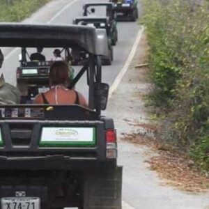 Four off-road vehicles travel in a line down a narrow paved road bordered by dry vegetation, with two people in each, enjoying The Hangover Offroad Tour—a guided outdoor adventure through scenic rural landscapes.