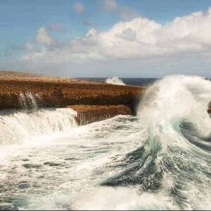 Experience the thrill of waves crashing against a rocky shore under partly cloudy skies as white foam soars above the rocks—all from a wooden viewing platform on the Wonderful World of Water Jeep Tour.
