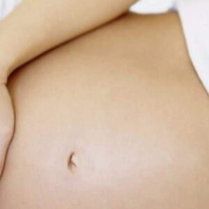 A relaxing Pregnancy Massage is shown with a close-up of a bare baby bump, a hand gently resting on the side. The blurred background and light-colored clothing highlight comfort and calm for expecting mothers.